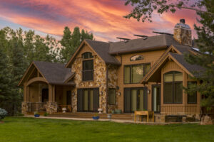 KGuard Rocky Mountains Install. Brown home with darker brown trim and roof. Has stone front . twilight with colorful sunset in background. vibrant green yard in front. Does Installing Gutter Guards Increase Your Home’s Value?