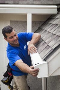 KGuard gutter installation. Installer is attaching the endcap to the newly installed KGuard leaf free gutter system. KGuard employee in blue shirt. KGuard gutter is white