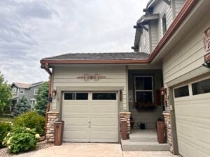 Copper Penny Open Gutters and downspouts. Gutters over garages in photo. copper accents and planters around a tan home.