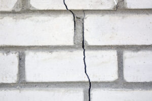White brick wall with foundation damage.