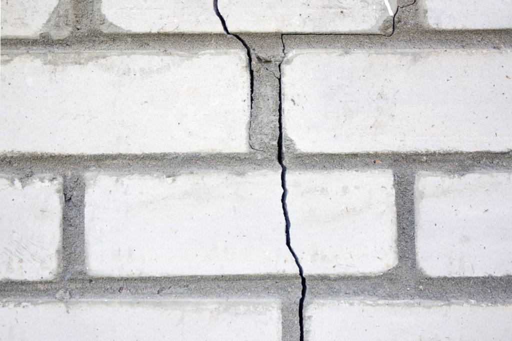 White brick wall with foundation damage.