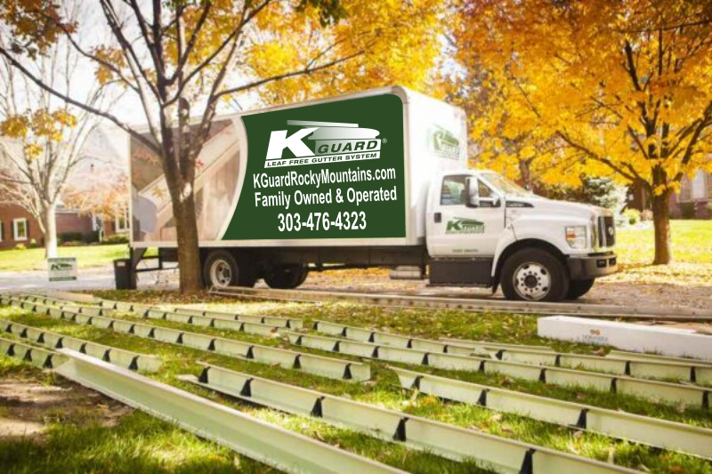 Photo of chop truck in front of home. fall trees in background. gutters are laid out on the front lawn with brackets set inside at every 2 feet.