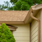 Light tan home with Light Brown gutters, downspouts and Gutter Guard. EZFlow Gutter Guard. Revers Curve aluminum Guard. Installed on K-style gutters. Installs under shingles