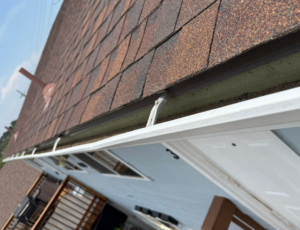 Standard Gutter Hail Damage. Open gutter damaged by hail. Open gutter hangers. Hangers installed through drip edge. Hanger damage from hail
