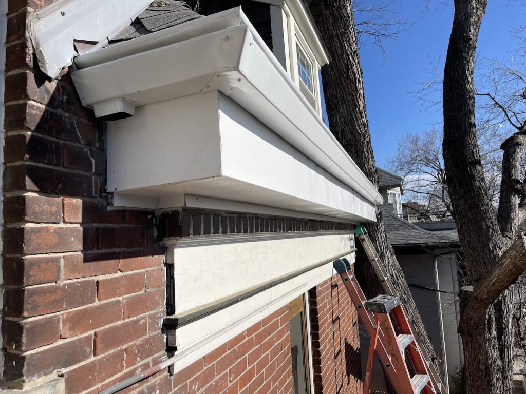 Gutter installation in Colorado Springs, white K-Guard Leaf Free system mounted along the eave of a brick home