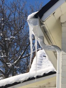 Icicles on mesh screens. Gutters with mesh screens. View from side of gutter, icicles are hanging down from the gutters.
