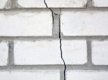 White brick wall with foundation damage.
