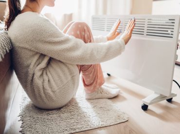 Woman Warming Her Hands in Front of an Electric Heater - K-Guard Rocky Mountains