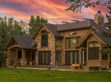 KGuard Rocky Mountains Install. Brown home with darker brown trim and roof. Has stone front . twilight with colorful sunset in background. vibrant green yard in front. Does Installing Gutter Guards Increase Your Home’s Value?