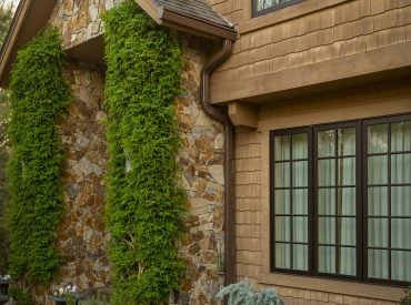 KGuard installed on home with brown siding and stone accents. Well maintained landscaping and bushes. Gutters protecting landscaping. Well maintained yard