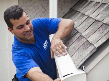 KGuard gutter installation. Installer is attaching the endcap to the newly installed KGuard leaf free gutter system. KGuard employee in blue shirt. KGuard gutter is white
