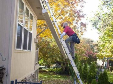 A picture of a man climbing a ladder to perform gutter maintenance