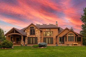 Rear elevation of a large stone-and-shake Colorado home at sunset with K-Guard gutters running along every roofline