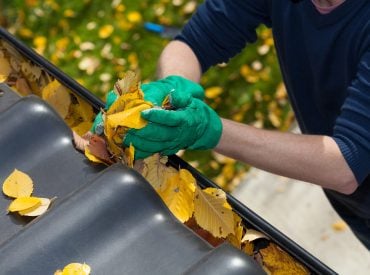Cleaning,The,Rain,Gutter,During,Autumn,,Horizontal