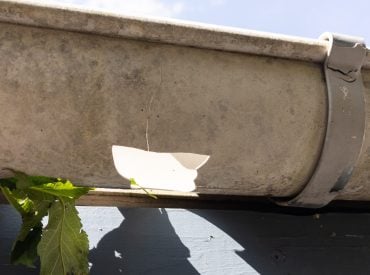 Damaged half round gutter. Hole in bottom of gutter. How Long Do Vinyl Gutters Last in Colorado
